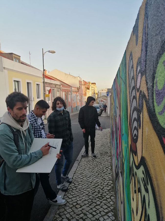 Grupo de jovens a assinalar as obras de arte urbana no bairro.